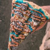 Cookie Monster dessert pizza slice - blue vanilla icing, cookie dough, Oreo crumbles and Nutella drizzle - Brother Bruno Direct