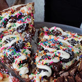 Slutty Brownie dessert pizza slice - Nutella base, cookie dough, brownies, crushed Oreos and cream cheese icing - Brother Bruno Direct
